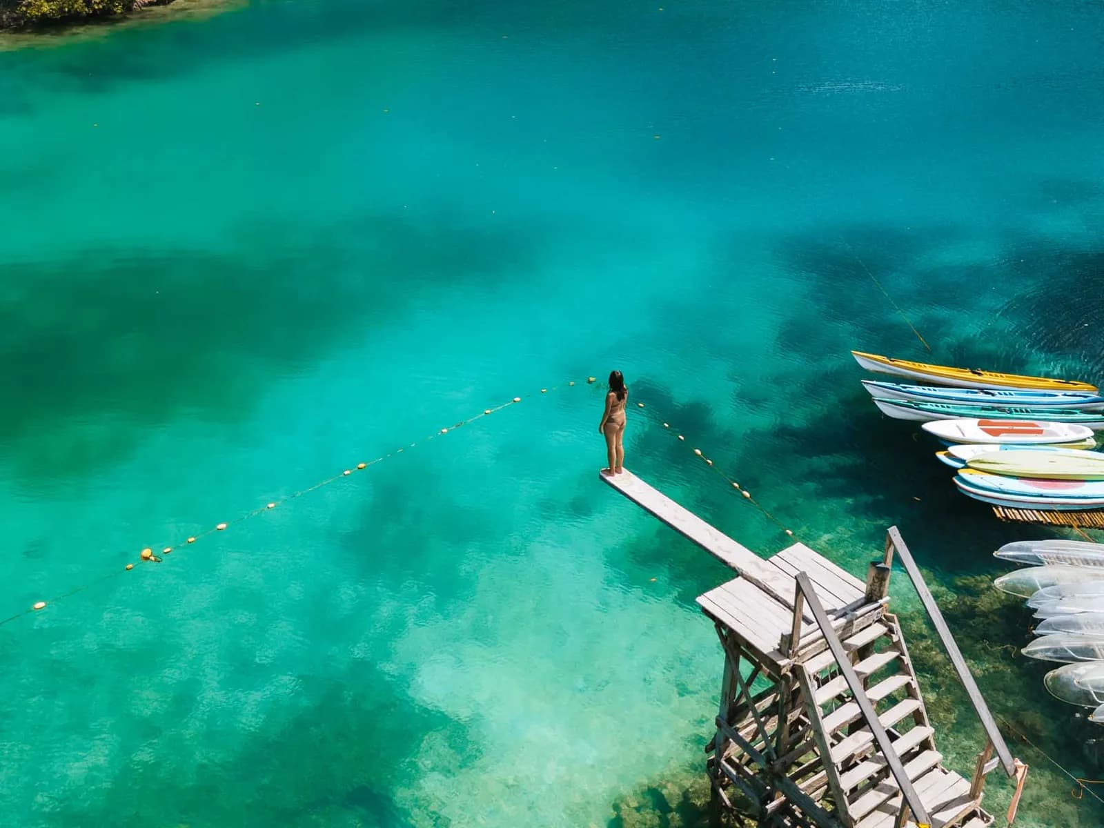 A traveler on the wooden diving board over the clear turquoise water of Sugba Lagoon, Siargao